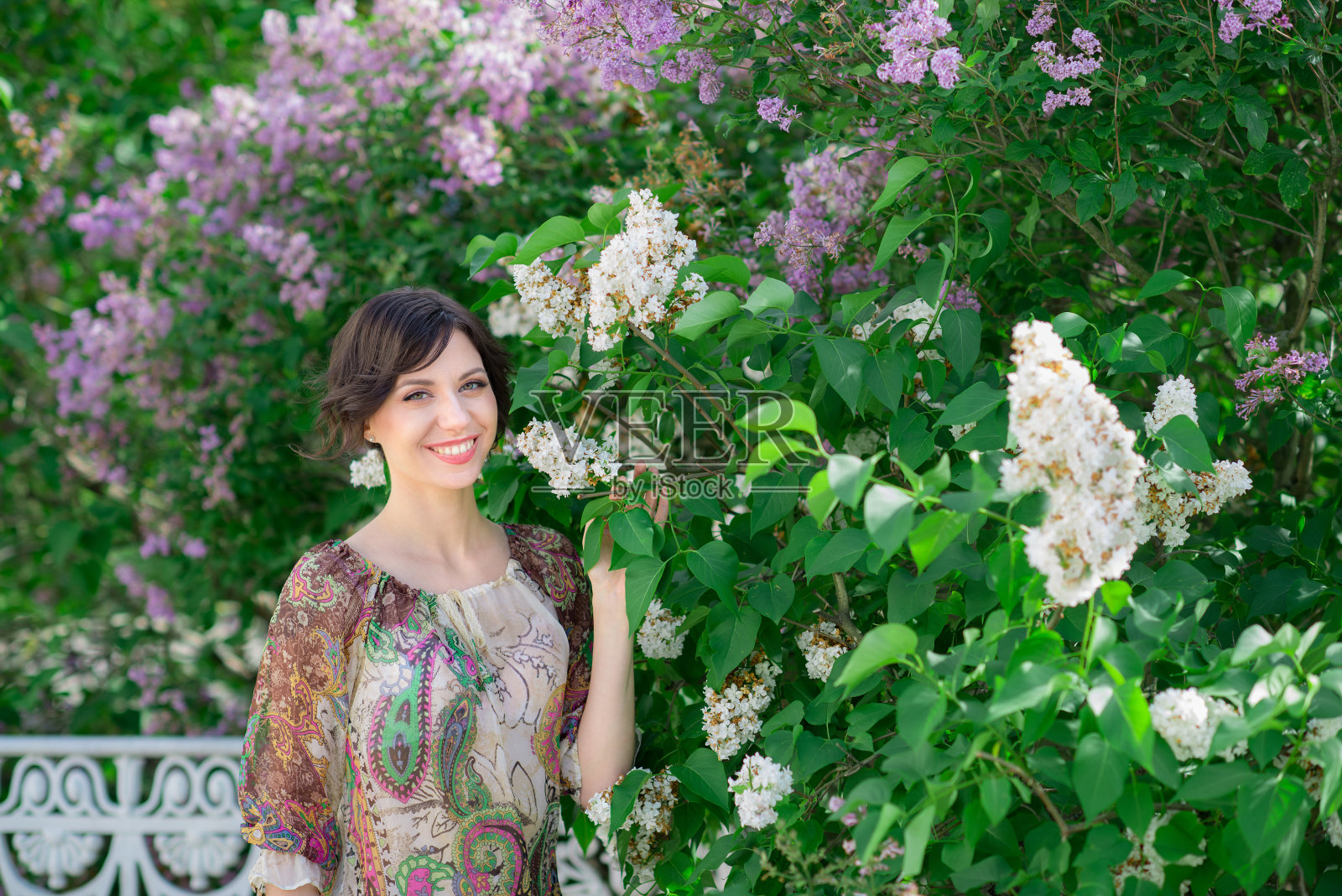 花背景上的漂亮女人。春天的美丽。美丽的女孩享受着丁香的香味照片摄影图片