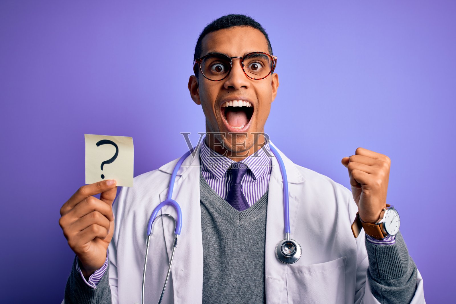 英俊的非裔美国医生男子戴着听诊器举着问号提醒尖叫自豪，庆祝胜利和成功非常兴奋，欢呼的情绪照片摄影图片