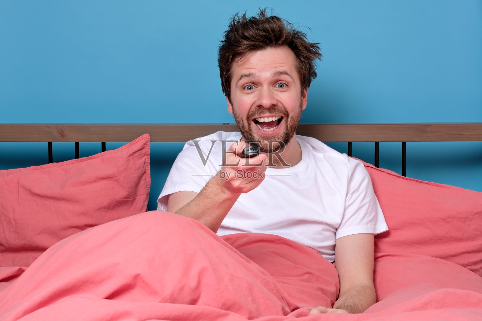 年轻人兴奋地看电视或电影，用遥控器时兴奋。照片摄影图片