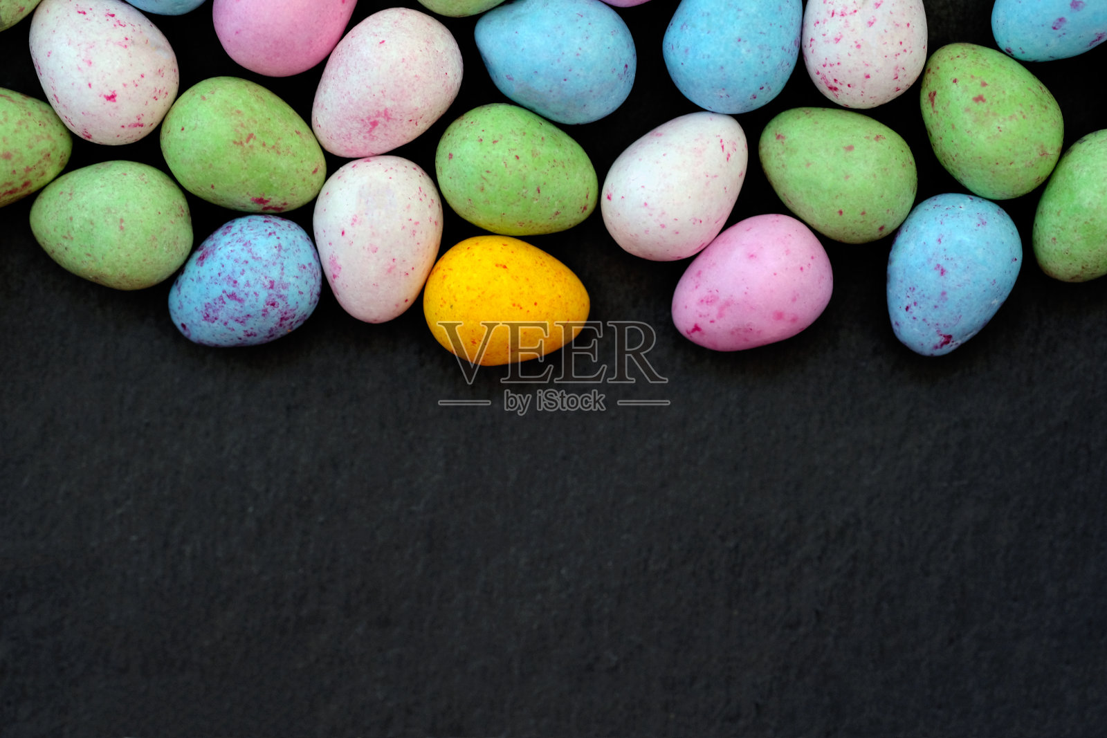 黑色背景上的鸡蛋形状的五彩糖果。照片摄影图片