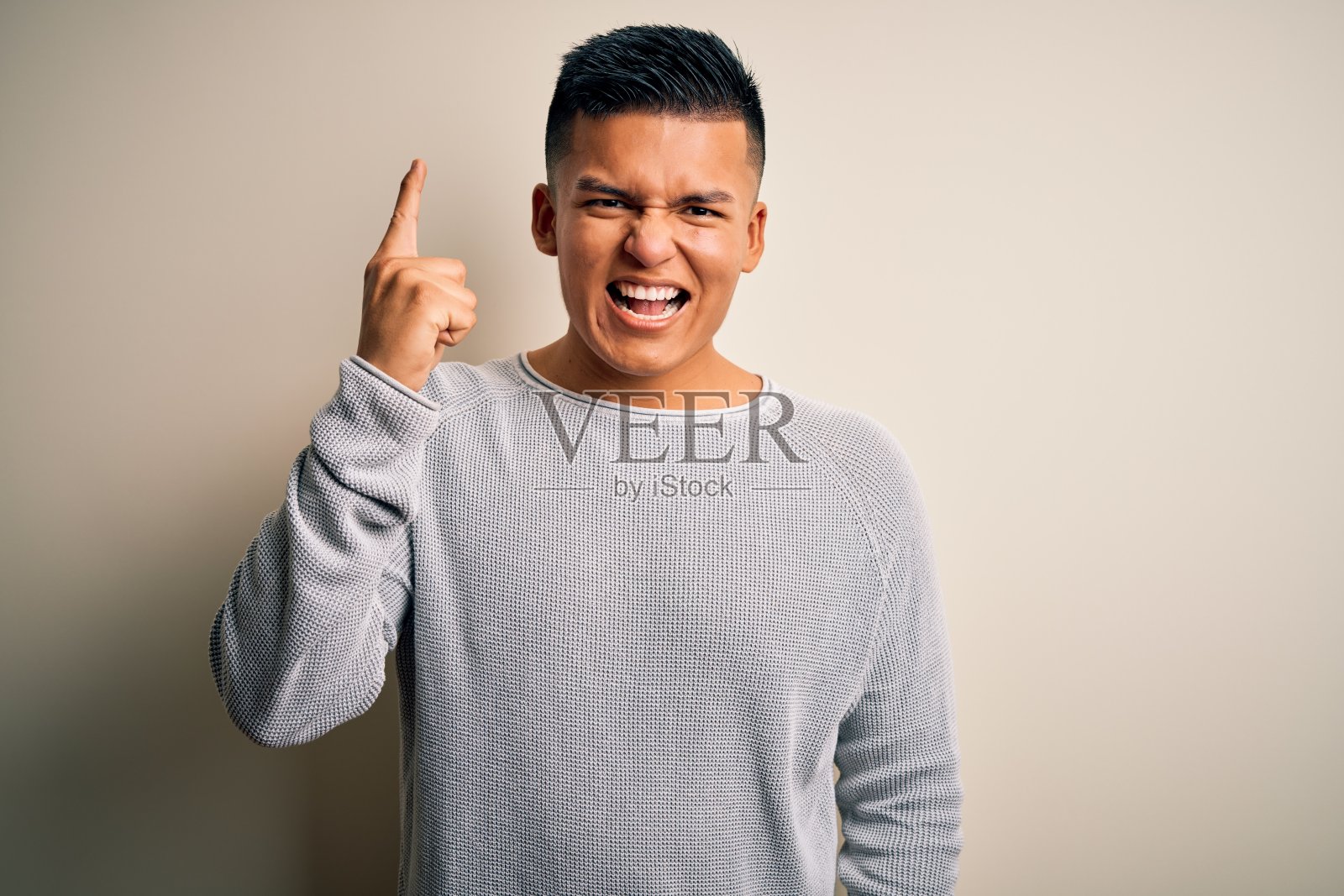 年轻英俊的拉丁男子穿着休闲毛衣站在孤立的白色背景指向手指与成功的想法。退出和快乐。第一。照片摄影图片