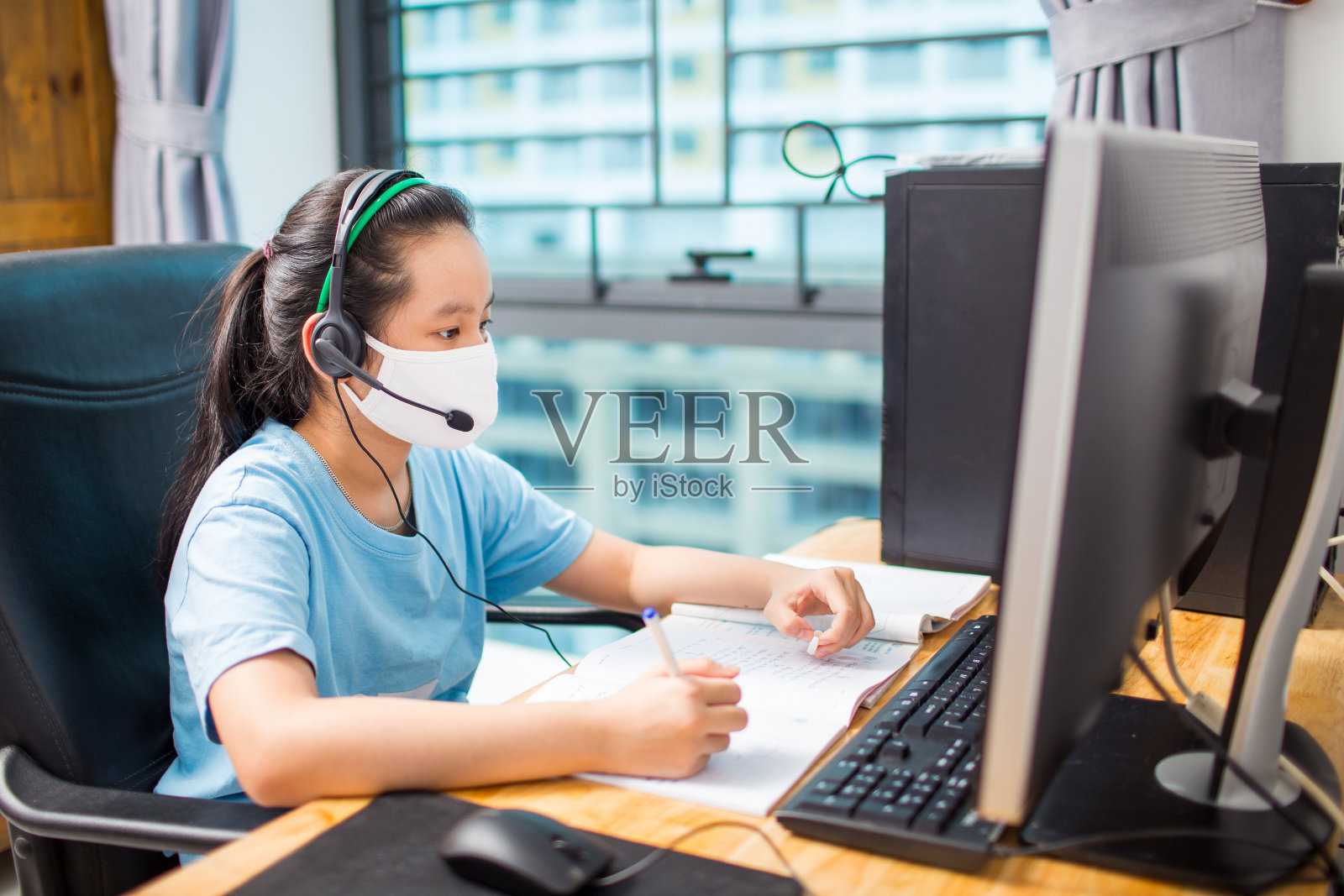 越南女孩戴着口罩在家里书桌上用电脑上网学习照片摄影图片