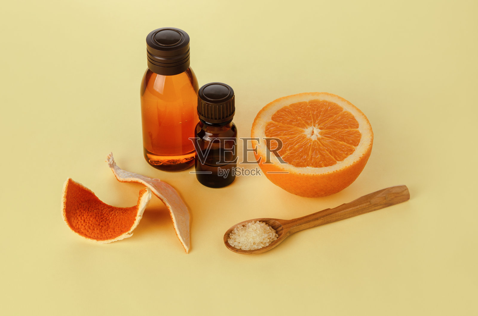 橙色精油在玻璃瓶上黄色的纸背景，自我护理和脂肪控制的概念照片摄影图片
