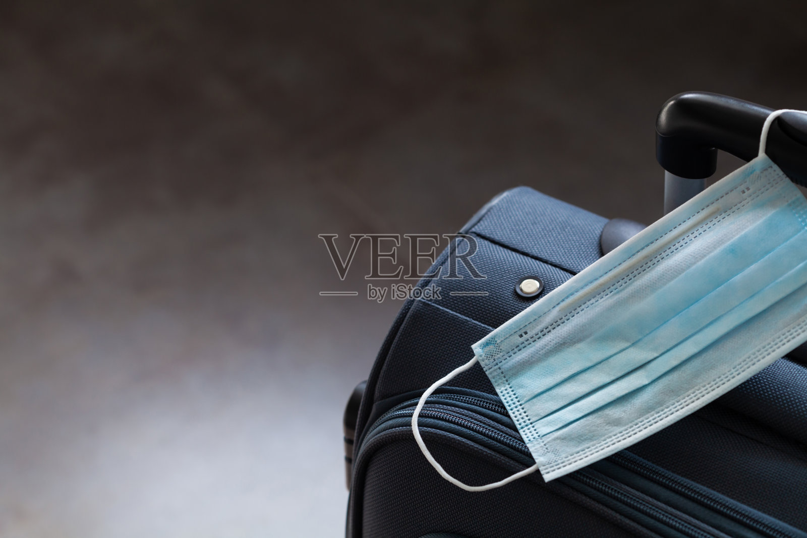 旅行箱和医用口罩新冠肺炎疫情期间的旅行禁令和隔离概念的引入。照片摄影图片