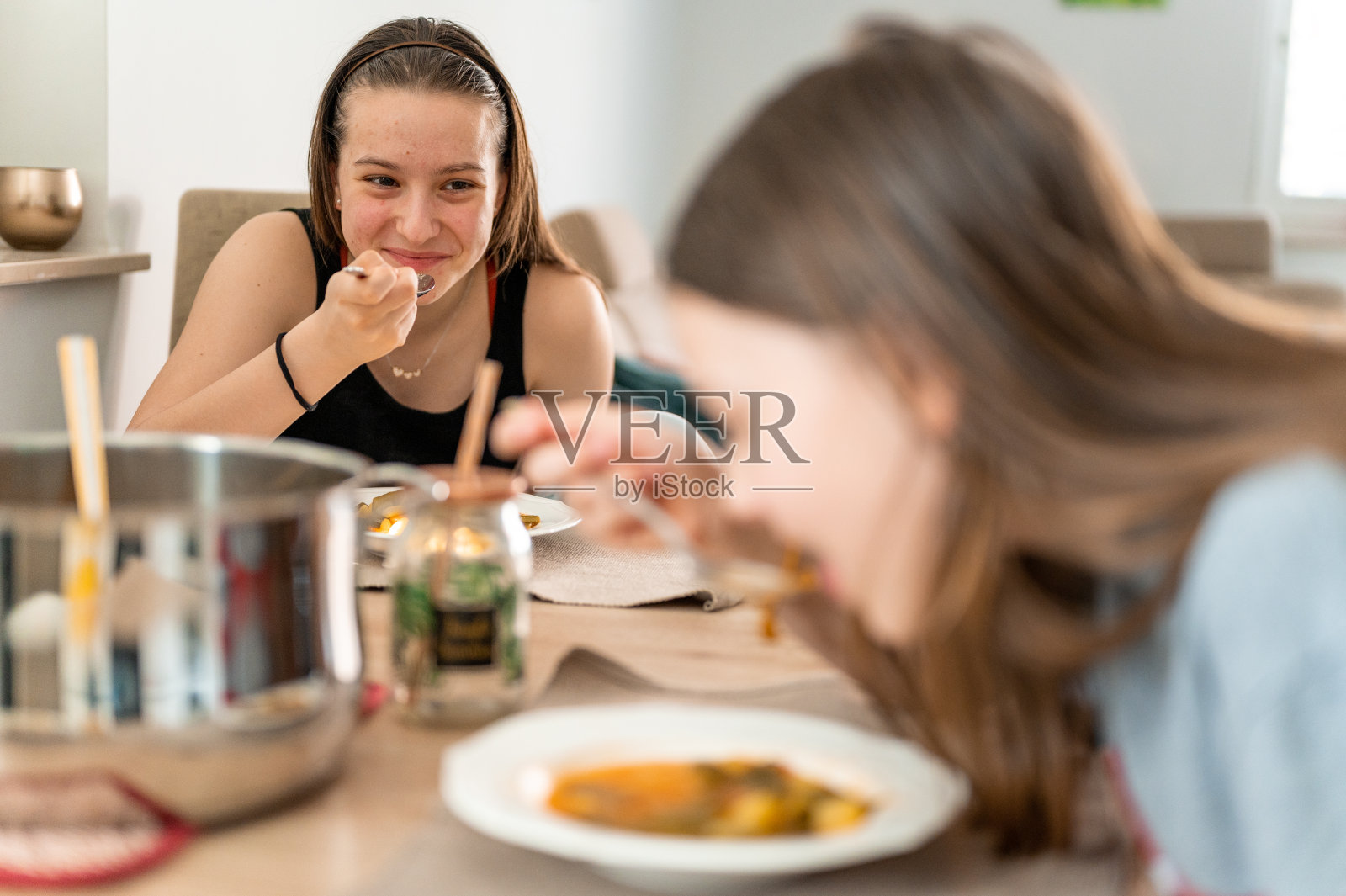 年轻女孩在家里喝蔬菜汤照片摄影图片