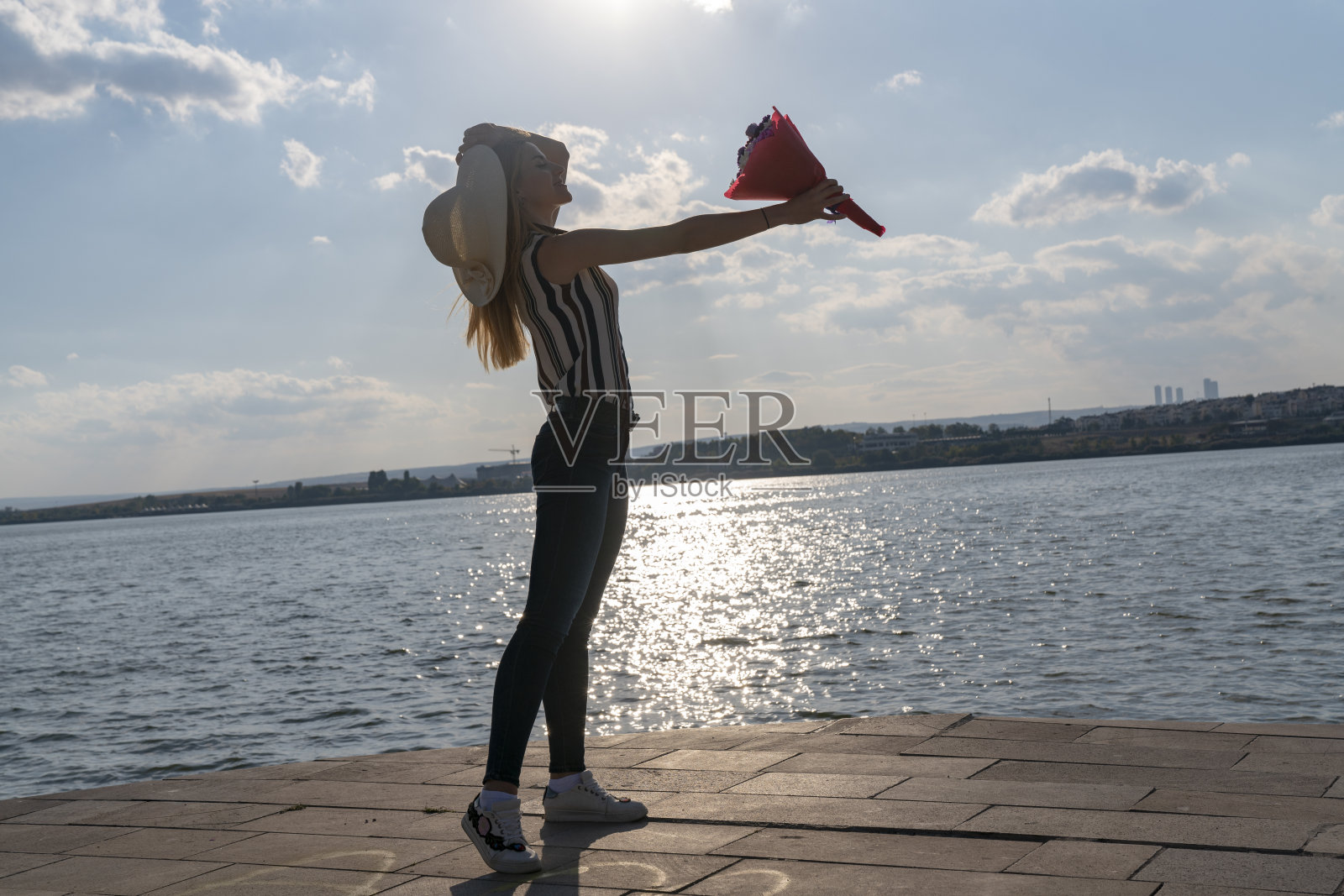 快乐的金发女人看着大海。快乐的女人从她海边的男朋友那里买了花照片摄影图片