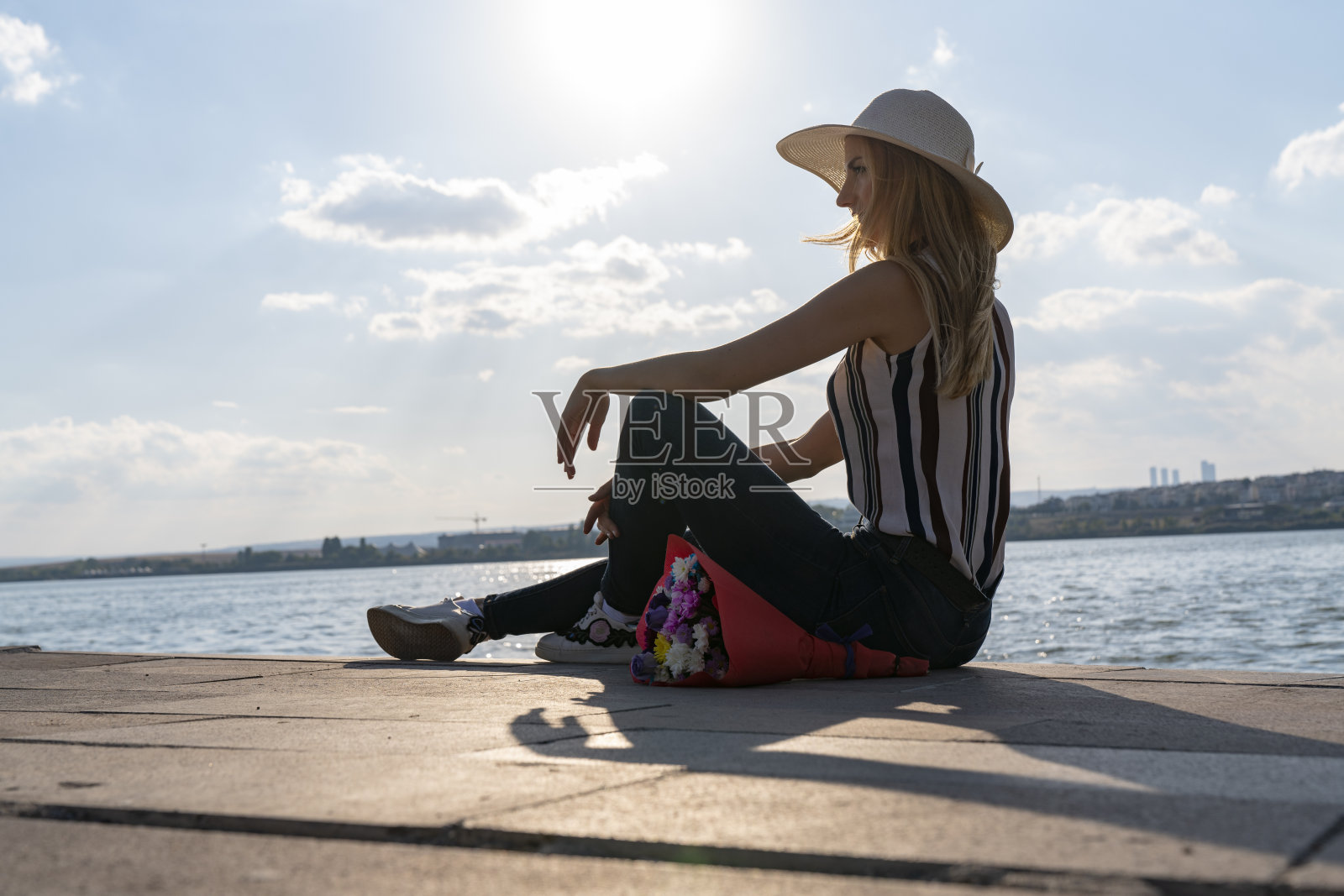 快乐的金发女人看着大海。快乐的女人从她海边的男朋友那里买了花照片摄影图片