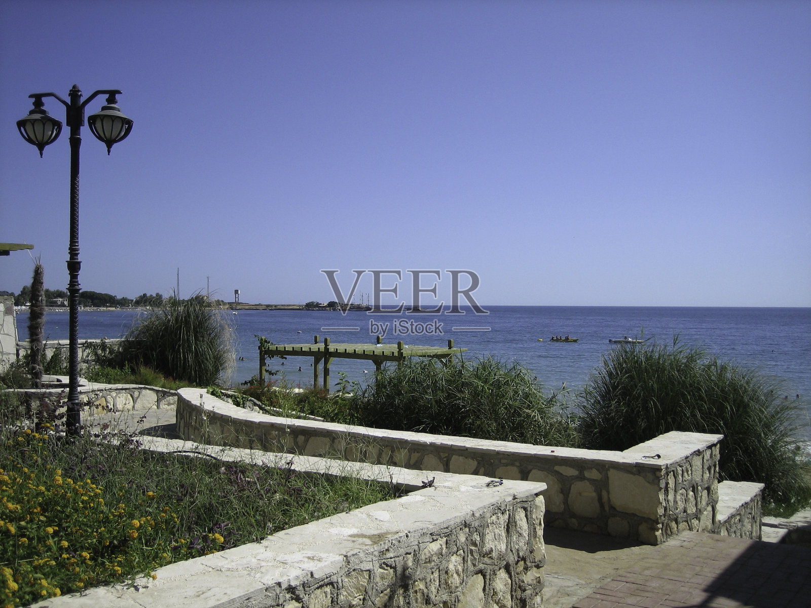 在晴朗无云的日子里，南海海岸是蓝色的。岸上有低矮的建筑物，常青的棕榈树等植被。照片摄影图片