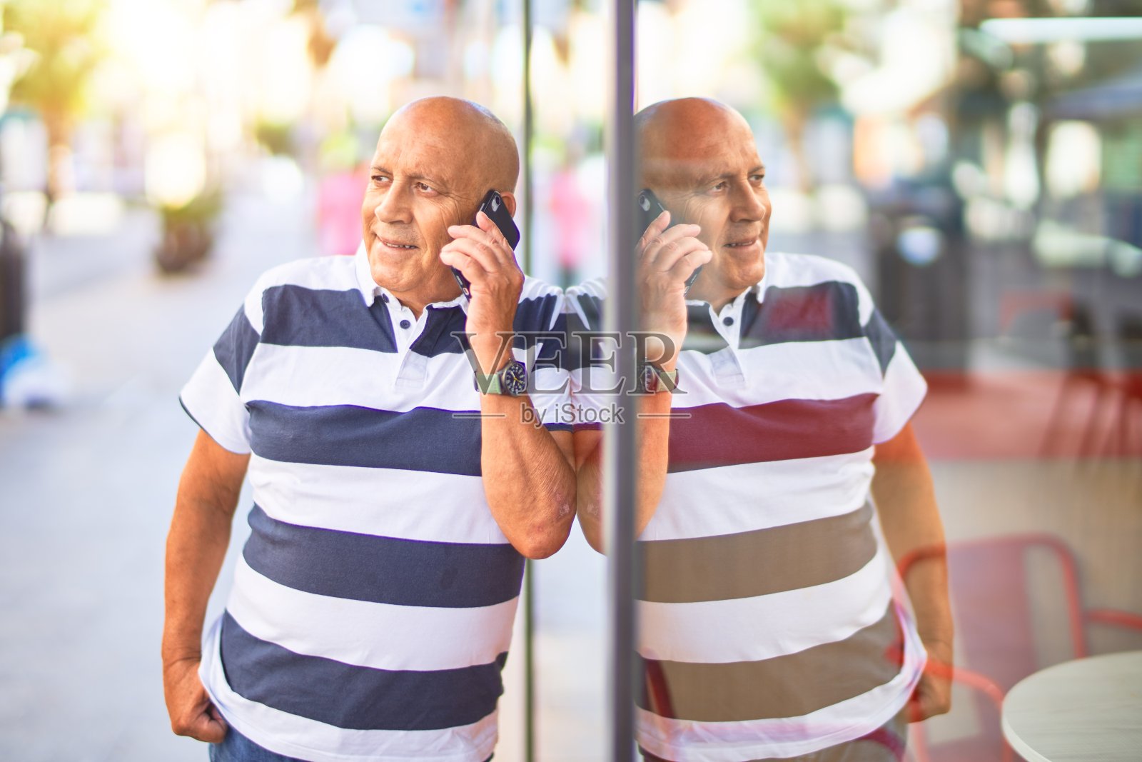 年长的男人在小镇街头对着智能手机微笑交谈照片摄影图片