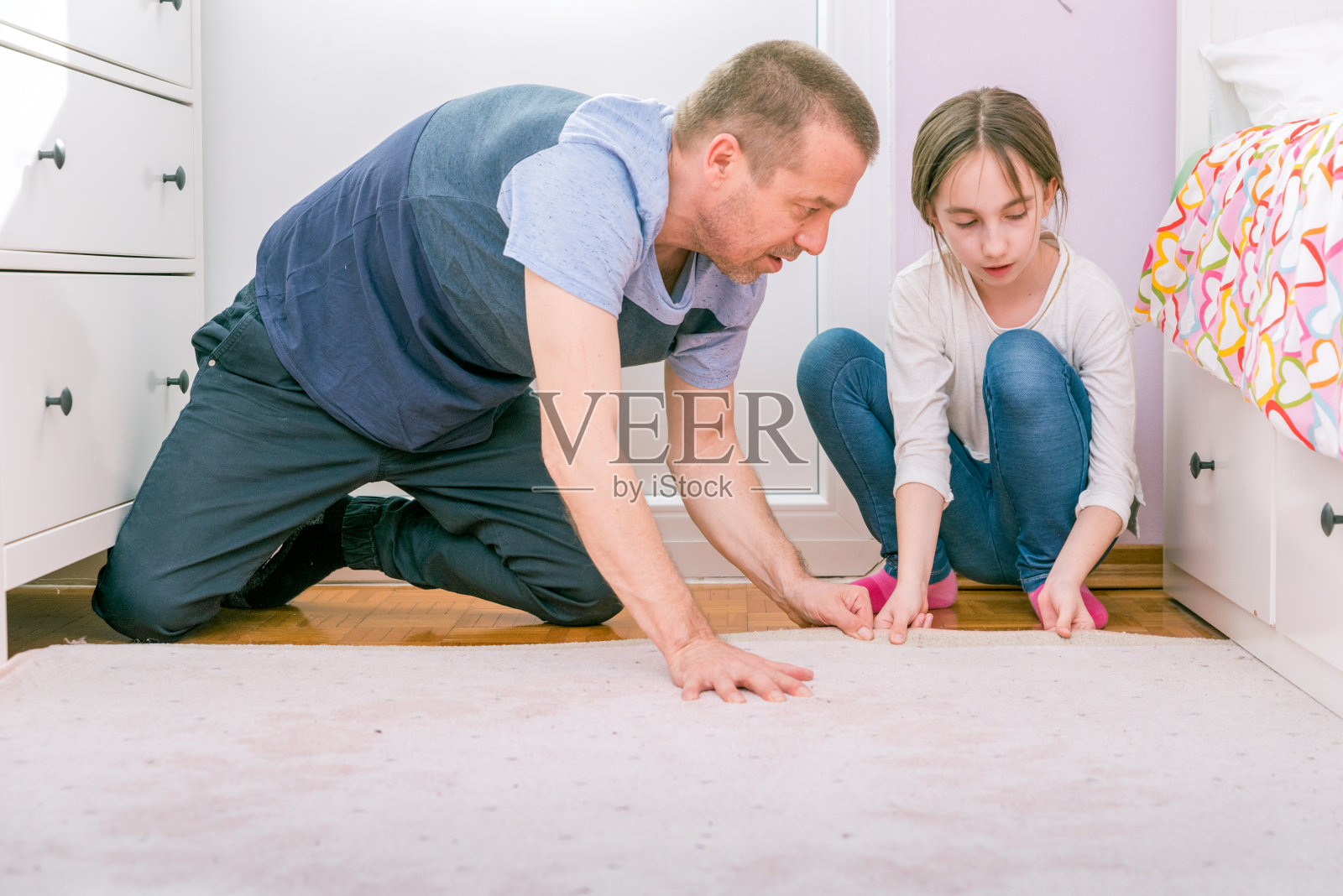 冠状病毒封锁期间，父亲给女儿的卧室铺了新地毯照片摄影图片