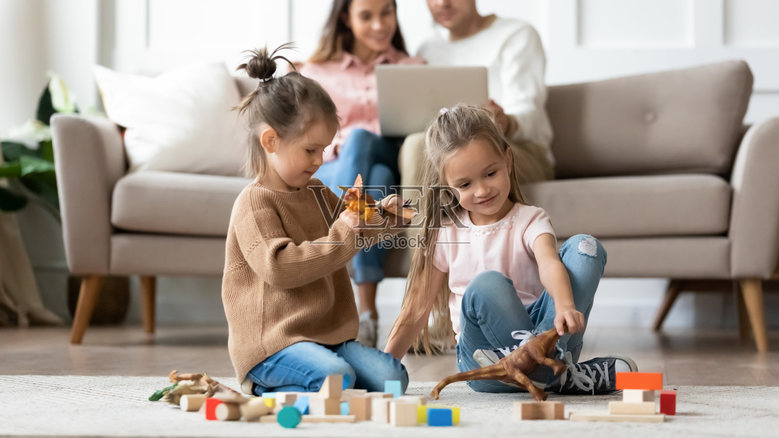 快乐的小妹妹们在地毯上玩玩具。照片摄影图片