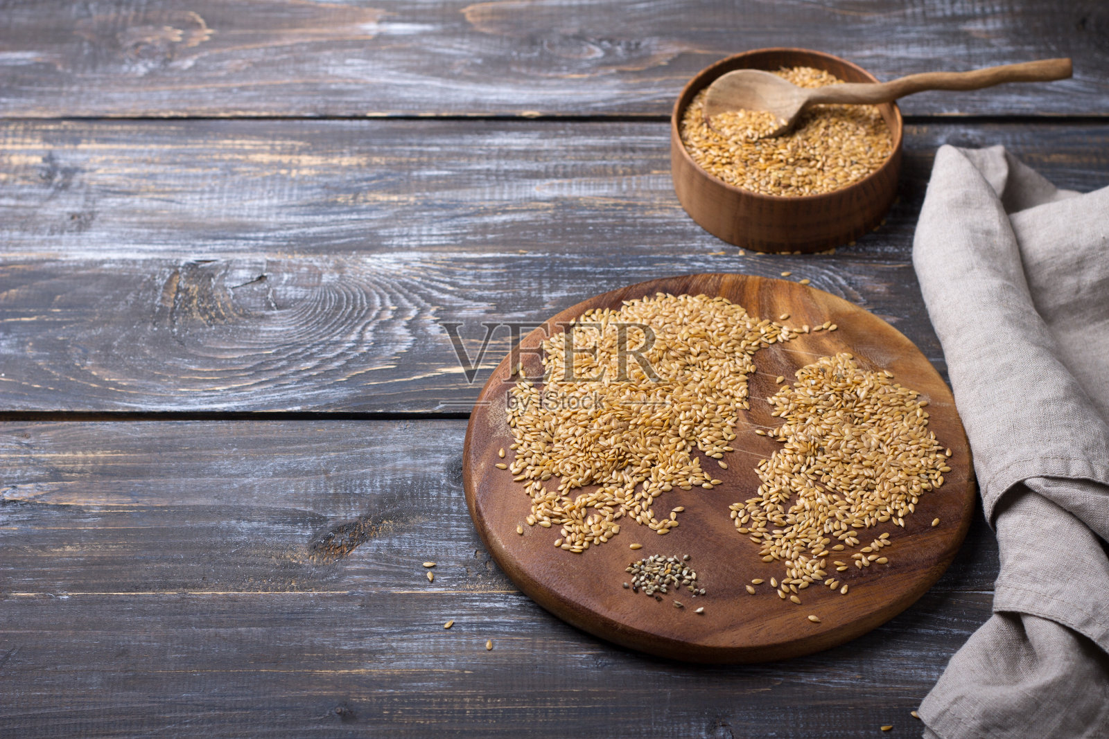 木桌上放着金黄色的亚麻籽。垃圾删除过程。健康的素食超级食物照片摄影图片