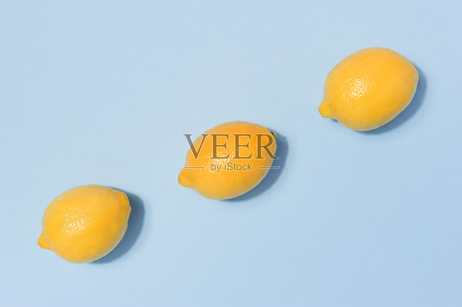 鲜柠檬对称地排列在蓝色的背景上照片摄影图片