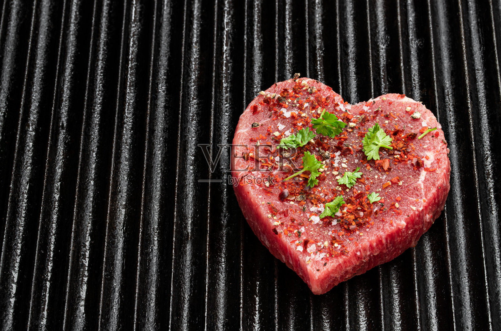 烤盘上放有香料的心型生牛肉。为肉食爱好者提供健康的生活方式或有机食品理念。照片摄影图片