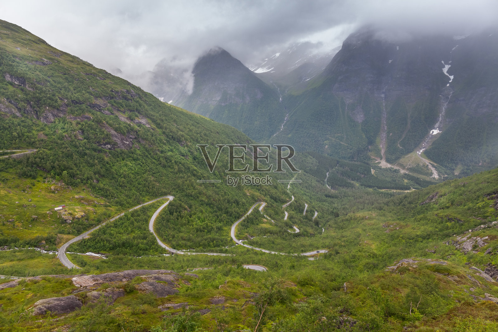 在挪威，一条土路穿过山谷之间的山脉，选择性的焦点照片摄影图片
