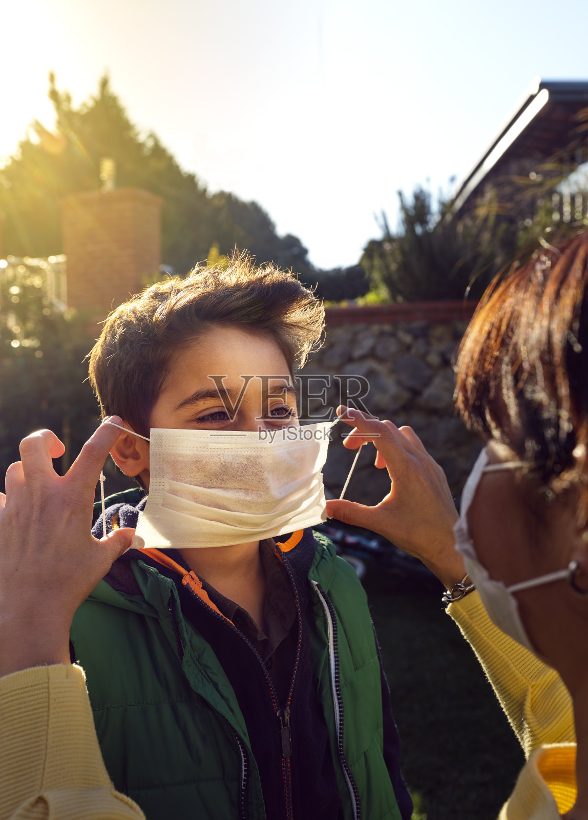 而她的母亲则戴着医用口罩，保护她的孩子免受Covid-19感染。照片摄影图片