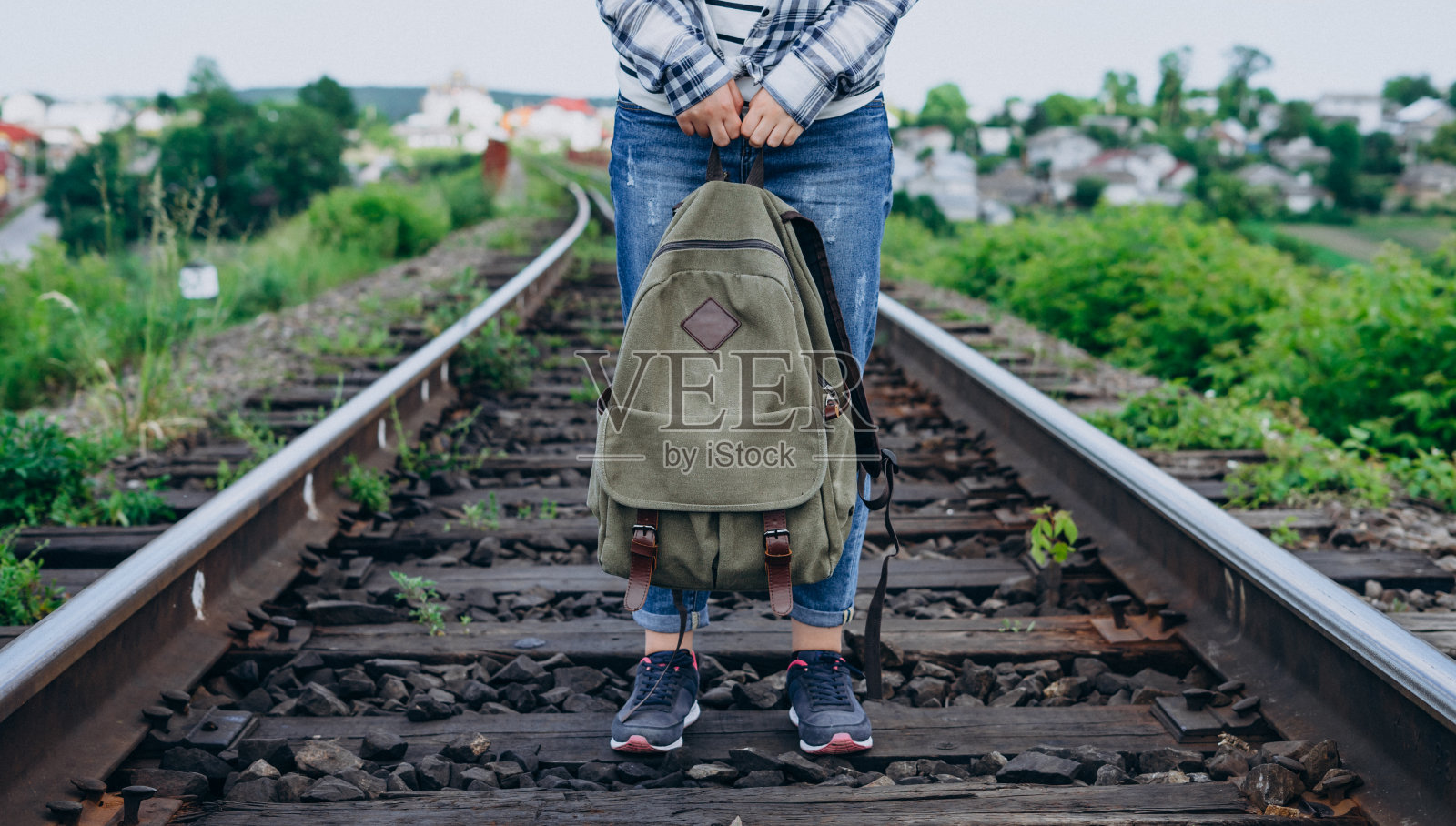 女子背着背包站在铁轨上。照片摄影图片