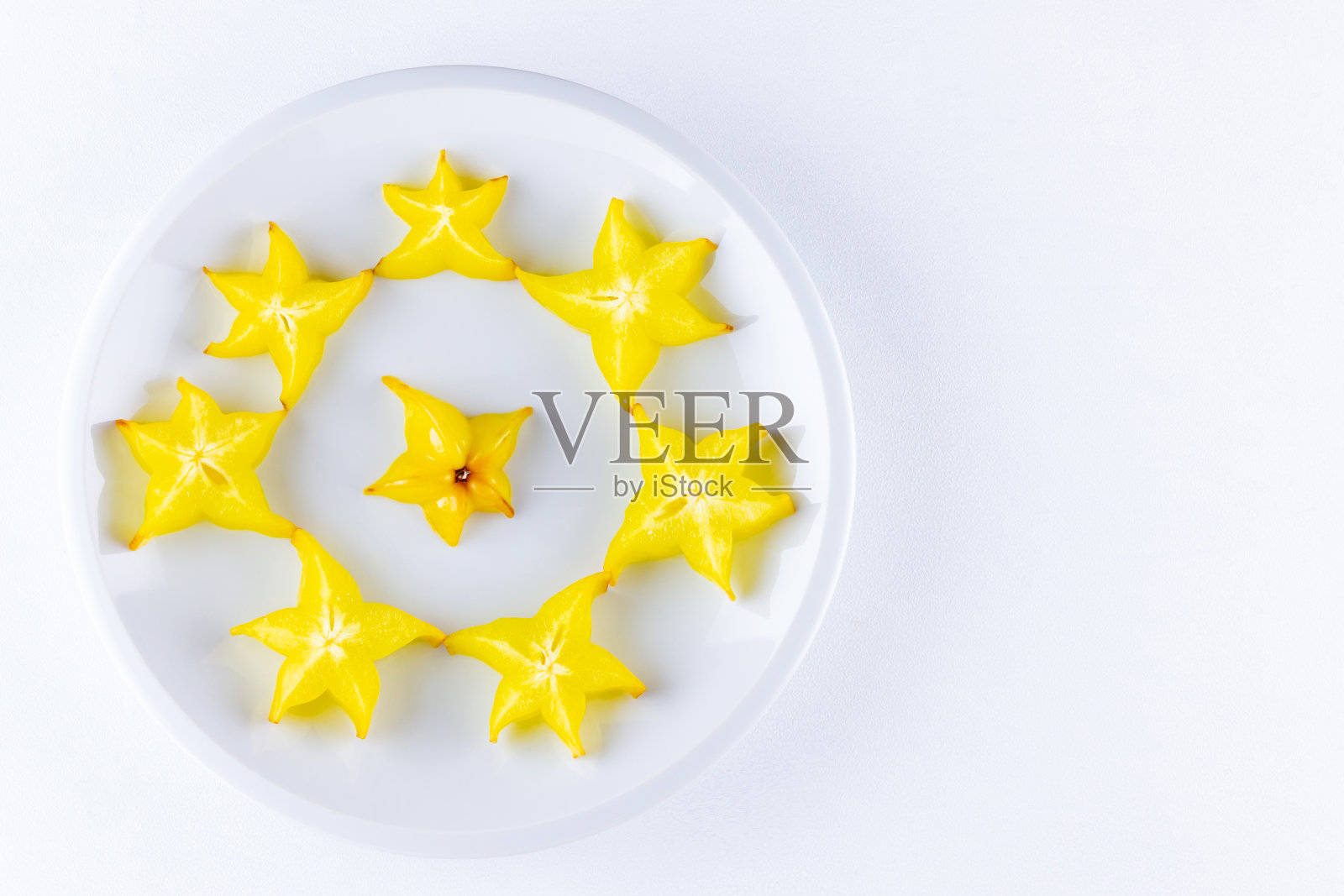 白盘上的杨桃。切片新鲜杨桃在白色的背景。杨桃片。时尚的食物照片摄影图片