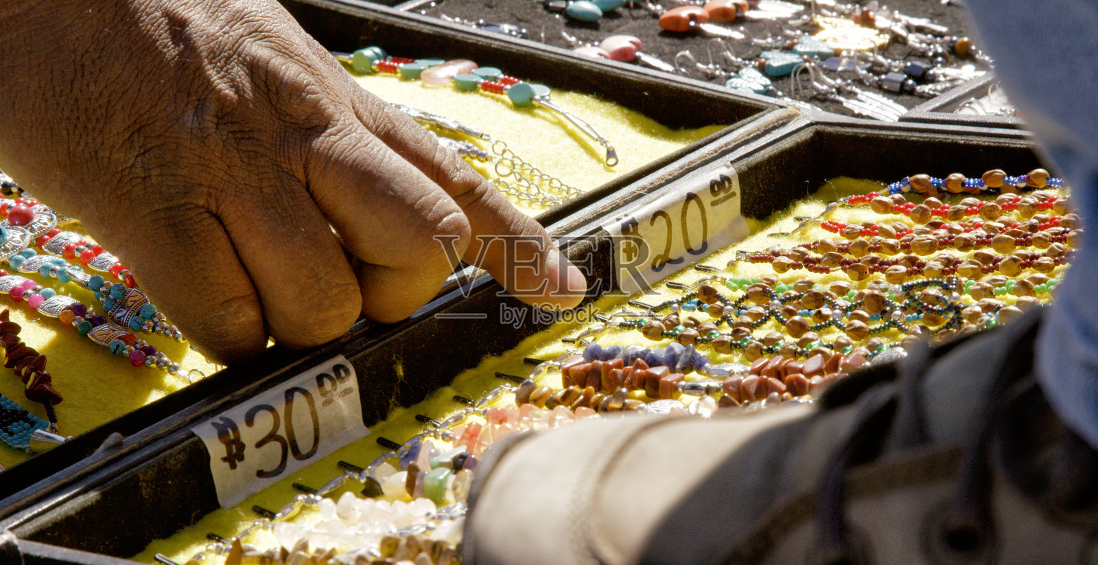 一位纳瓦霍人指向待售的美国原住民风格珠宝，附有价格照片摄影图片
