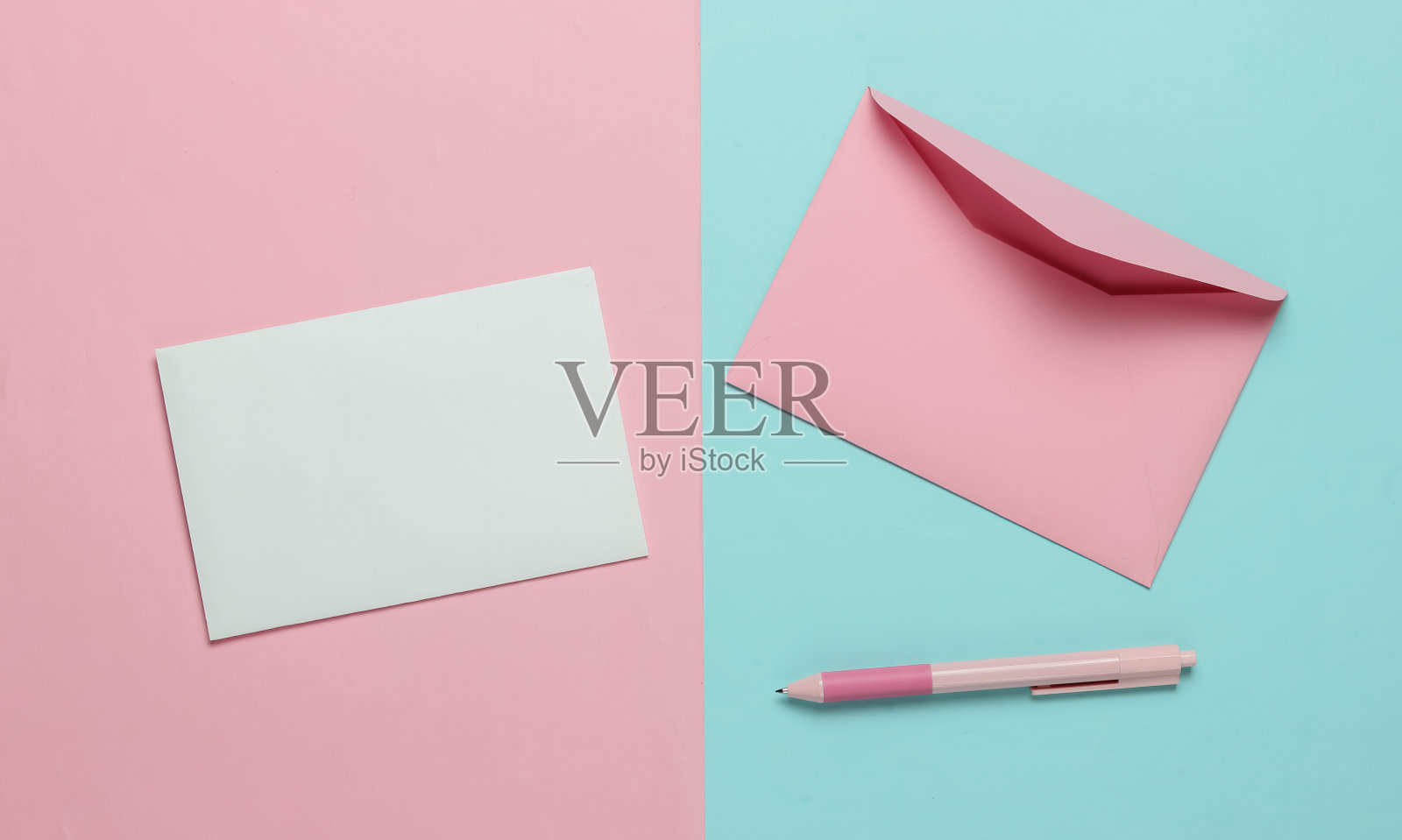 信封上有一封信和钢笔，背景是蓝粉色的。情人节，结婚或生日。俯视图照片摄影图片