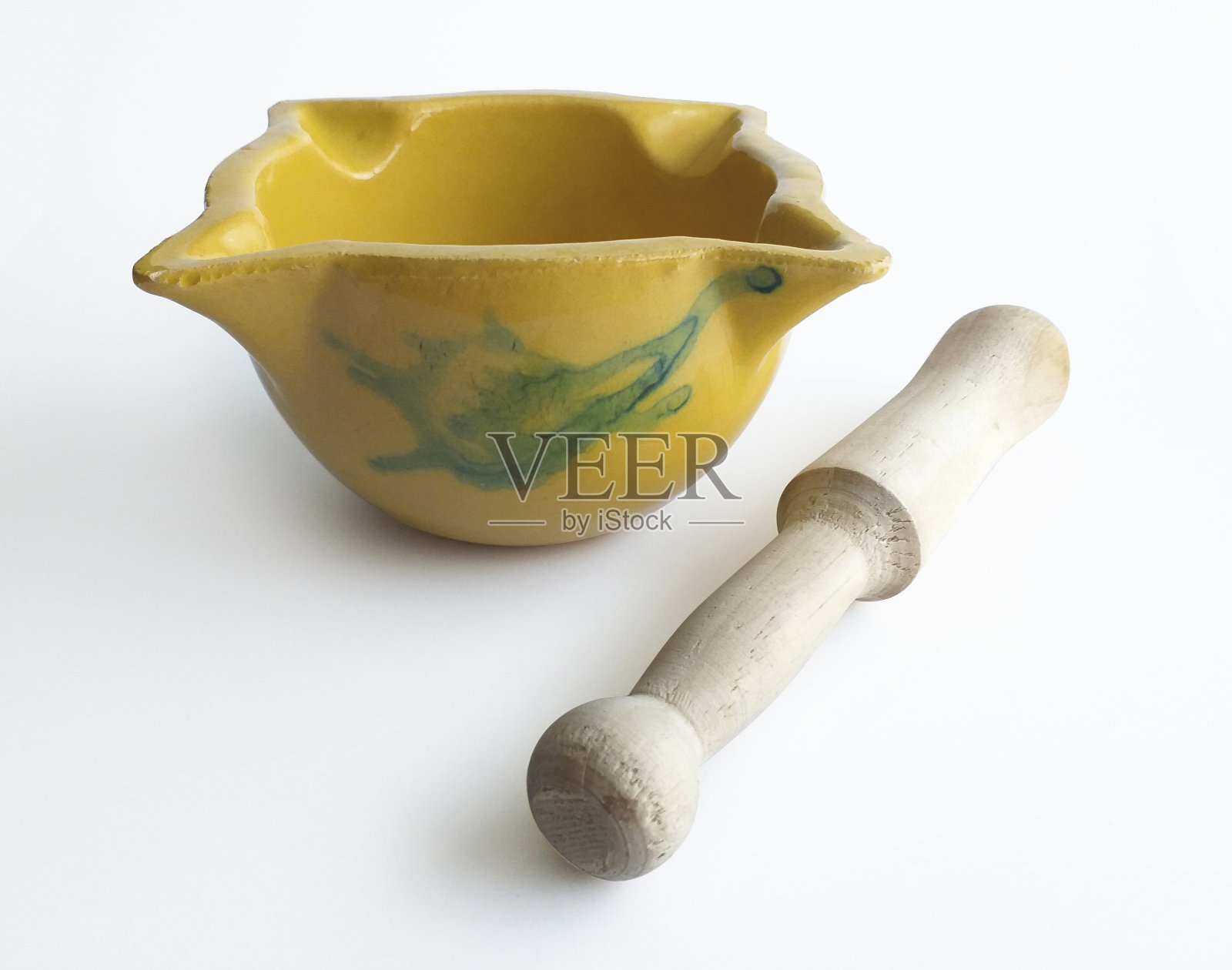 正面观旧陶浆黄色，空与木杵。绿色装饰。用黄色的灰浆做一种叫做Allioli的酱汁，西班牙加泰罗尼亚的典型，孤立在白色的背景上照片摄影图片