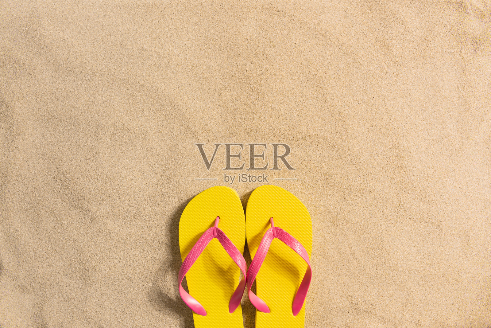 夏装时尚，夏装以沙为背景。黄色的人字拖在沙滩上。平躺，俯视图照片摄影图片