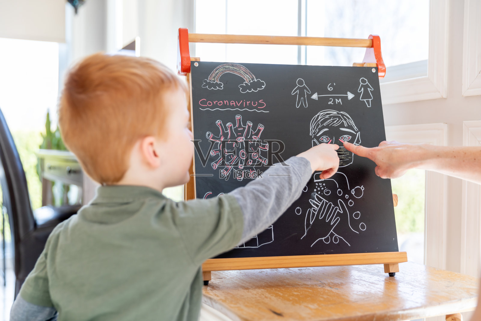 母亲教红发儿子关于冠状病毒和Covid-19照片摄影图片