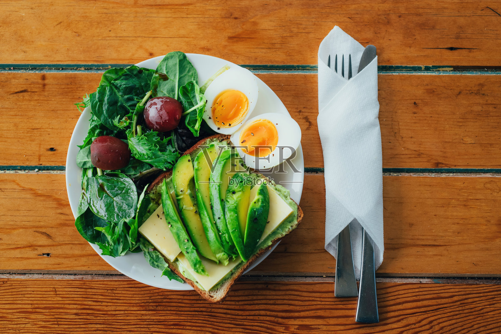 吐司配牛油果、水煮鸡蛋、菠菜，餐巾纸上刀叉照片摄影图片