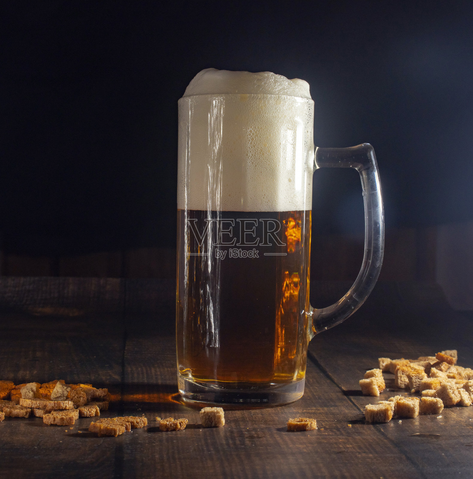 在一张木桌上放着一杯冰凉的冒着泡沫的啤酒。特写镜头。黑色背景。照片摄影图片