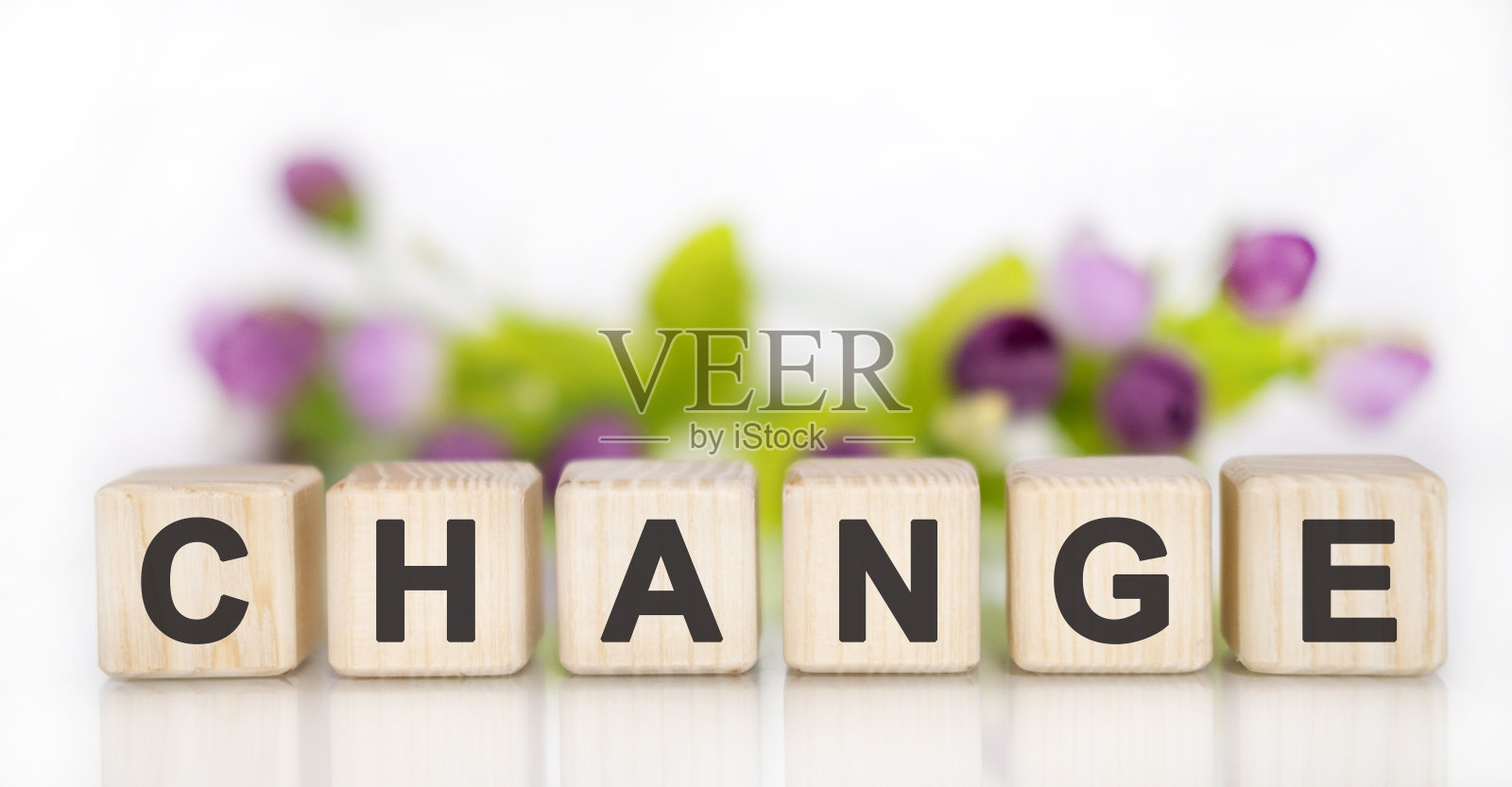 转变-财务经营理念。白色的桌子上放着木方。背景是粉红紫色的郁金香，一束花照片摄影图片