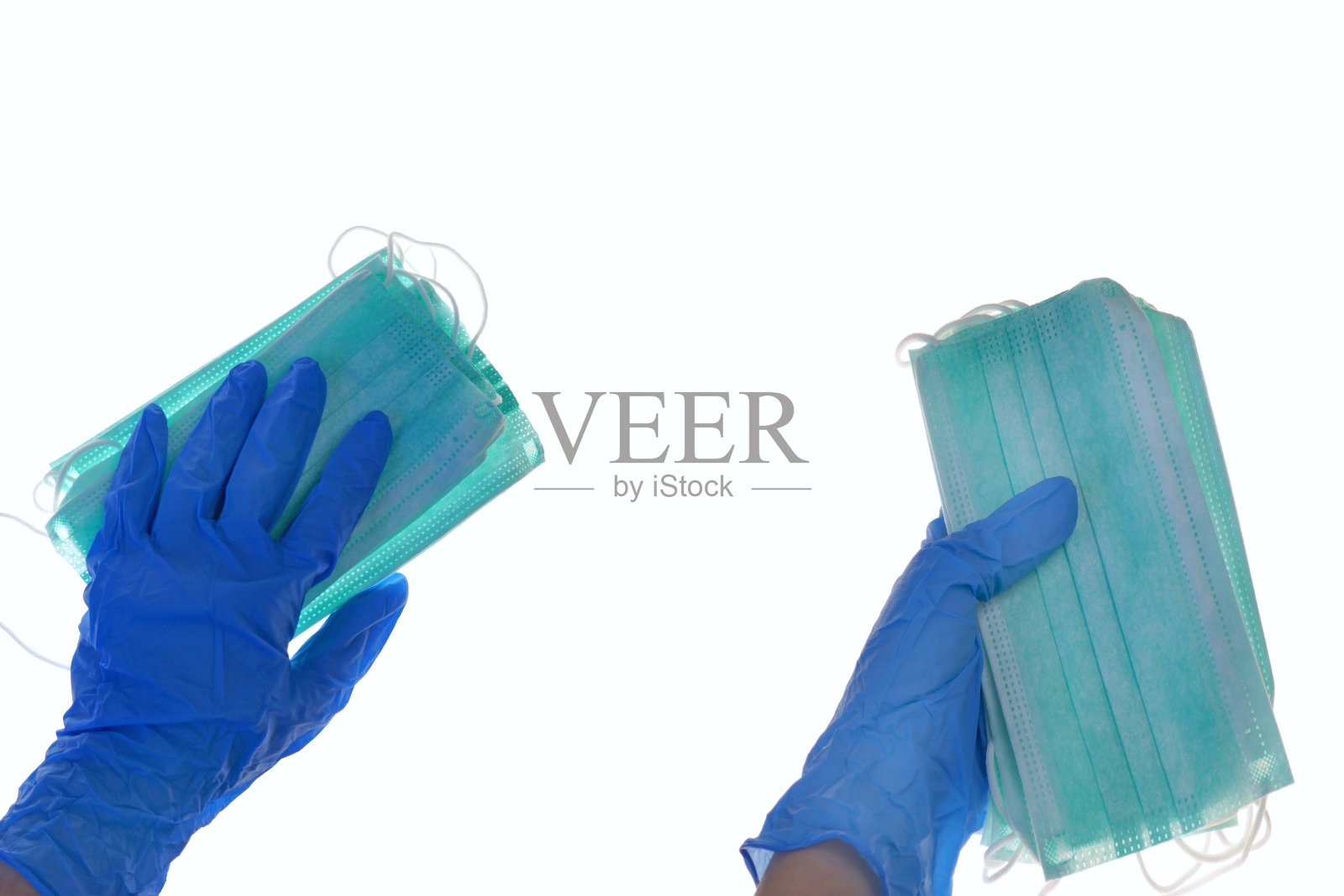 医用口罩和手套隔离在白色背景上。冠状病毒感染流行。预防感冒和流感。一只戴着蓝色手套的手拿着一包医用防病毒防护口罩套装。照片摄影图片