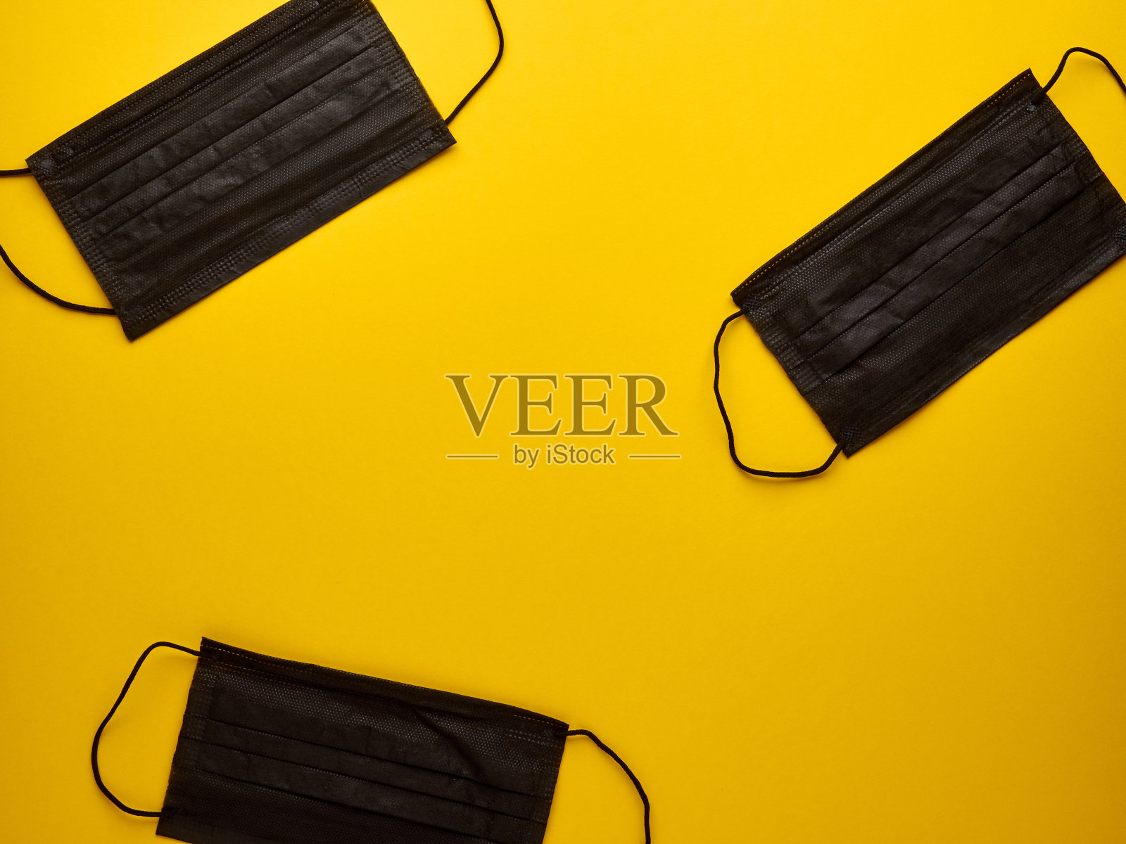 黄色背景上的三个黑色医用口罩照片摄影图片