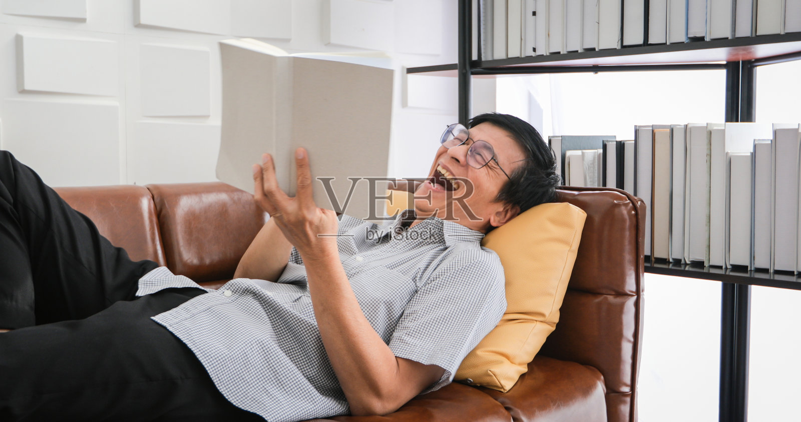 年长的亚洲男人在客厅沙发上看书，放松和快乐地在家阅读杂志照片摄影图片