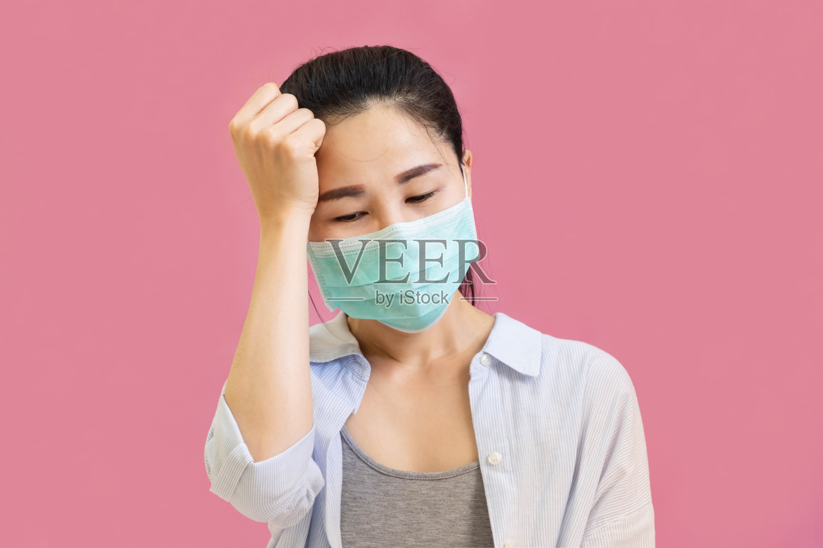 年轻美丽的亚洲女子身穿灰色汗衫，蓝色衬衫和防护口罩，对抗病毒和空气污染，隔离在粉红色的背景与红心，保健理念照片摄影图片