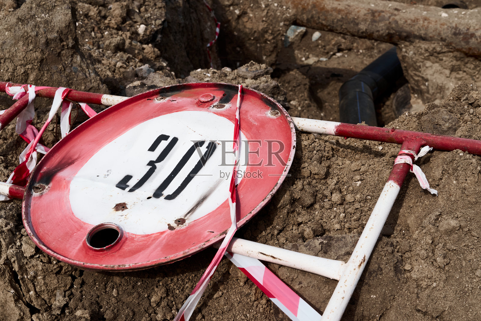 车速限制为每小时30公里或英里的道路标志和用于进行维修工作的道路围栏躺在地上照片摄影图片