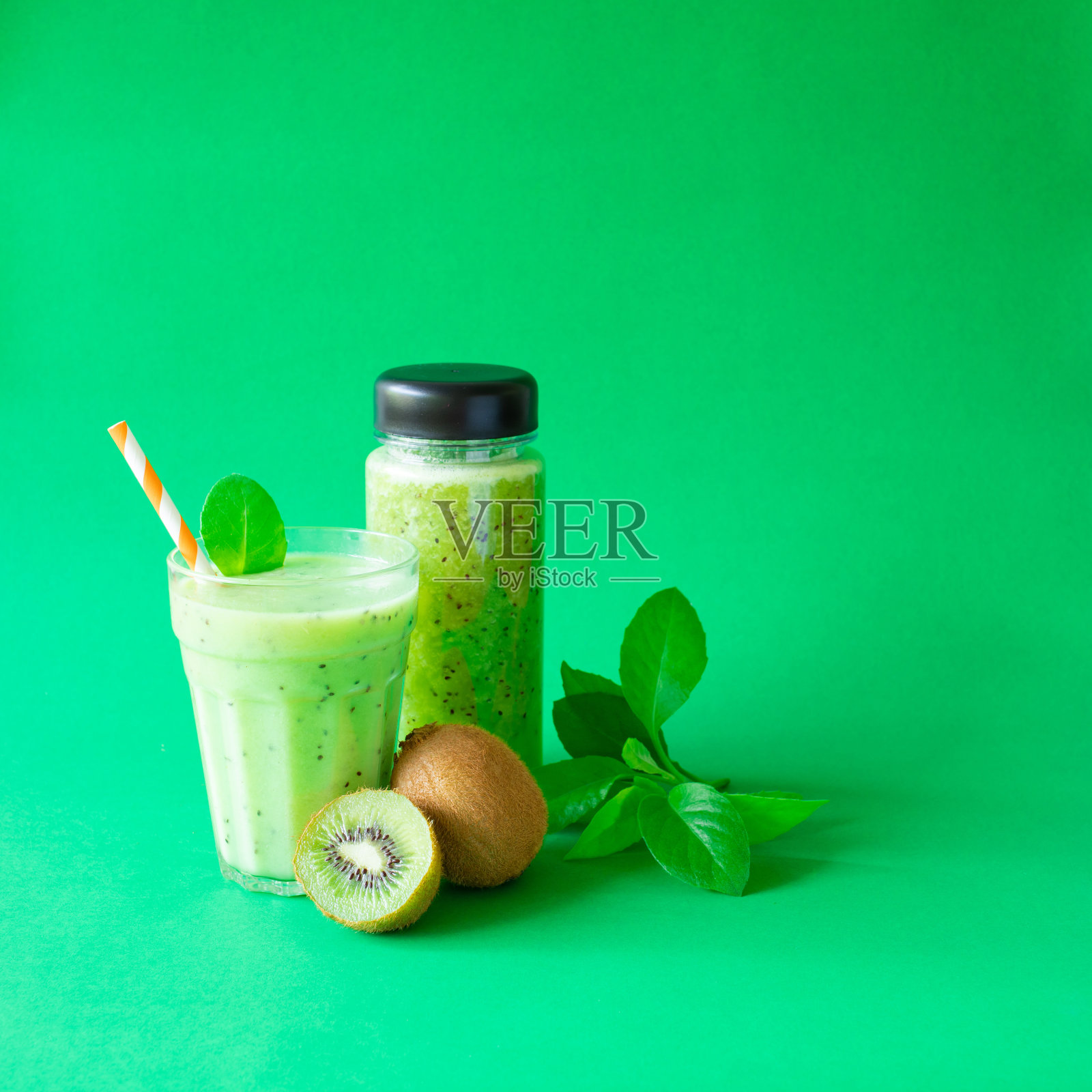 自制猕猴桃冰沙，用玻璃杯和瓶子在绿色的背景下照片摄影图片