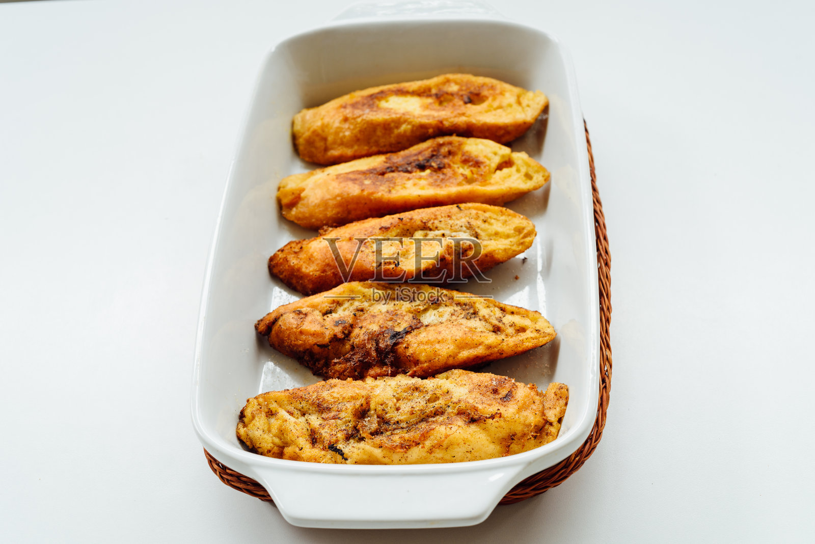 托里亚斯(Torrijas)，典型的西班牙甜炸吐司，将切片面包浸泡在鸡蛋和牛奶中，放在托盘上，孤立在白色背景上照片摄影图片
