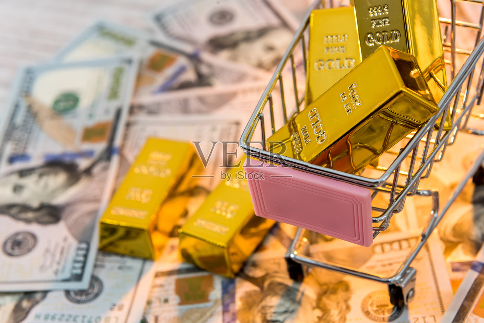 购物车里放着金条，背景是美元。金钱、财富和富足的概念。照片摄影图片