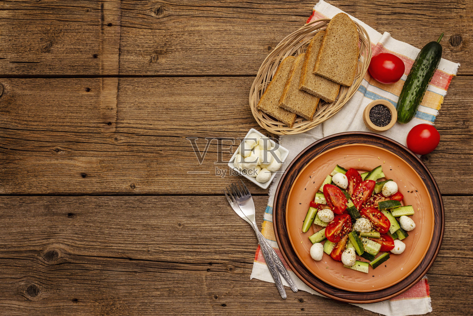 新鲜的西红柿，黄瓜和马苏里拉奶酪沙拉。阳光明媚的午餐配硬皮面包照片摄影图片