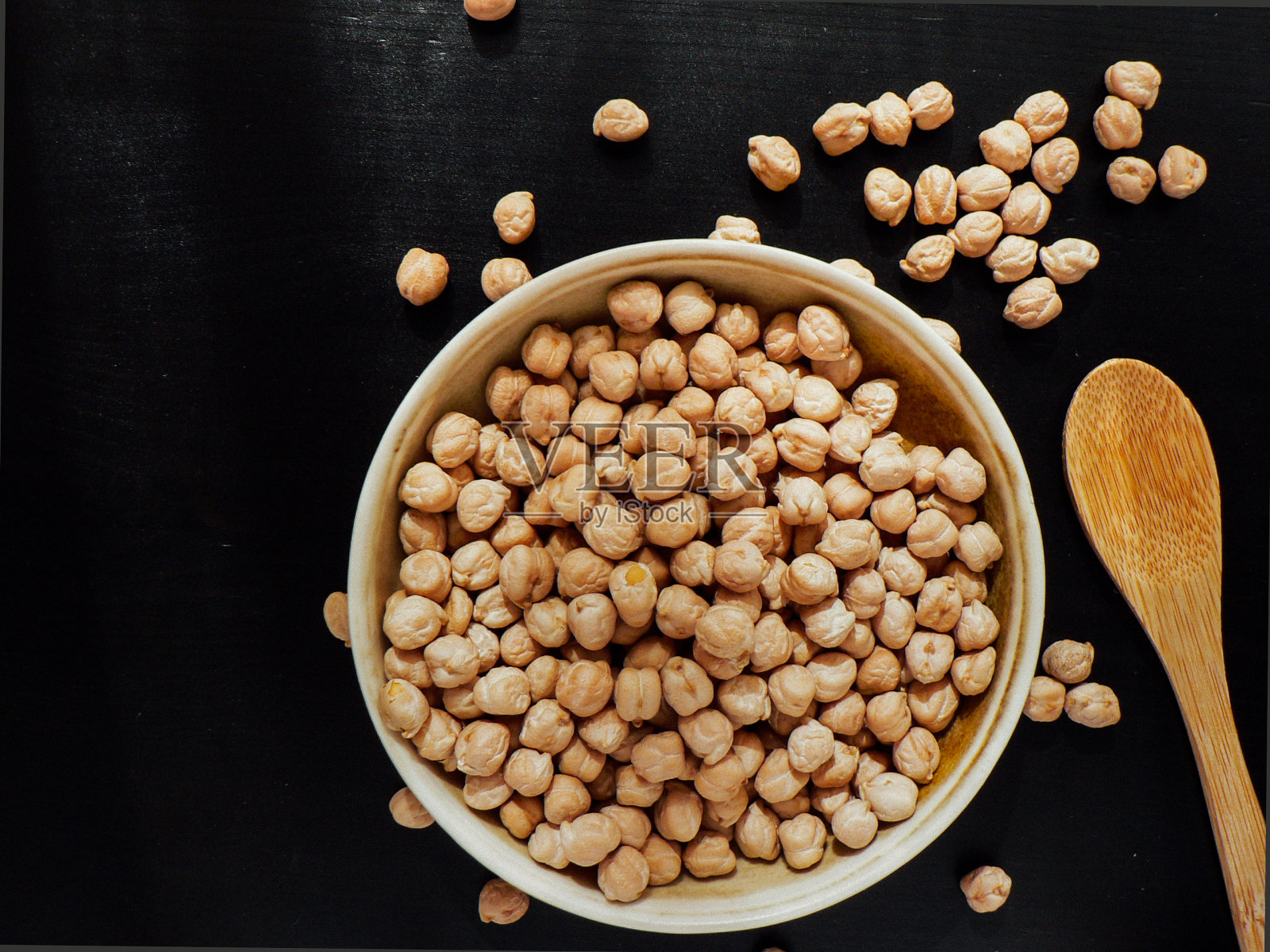 干的生鹰嘴豆放在棕色粘土碗里，放在木头上照片摄影图片