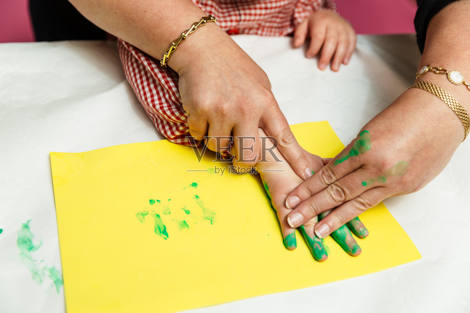治疗工艺课上，老师帮助残疾男孩用手和绿色颜料画黄色卡片照片摄影图片