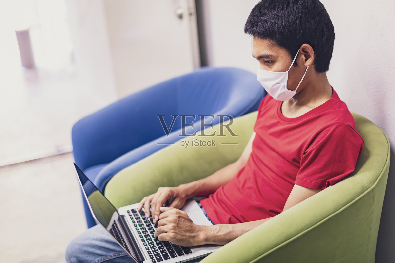 亚洲男性在冠状病毒或新冠肺炎期间在家工作。戴口罩预防冠状病毒，在家工作和使用平板。在家工作，待在家里。社会距离。照片摄影图片