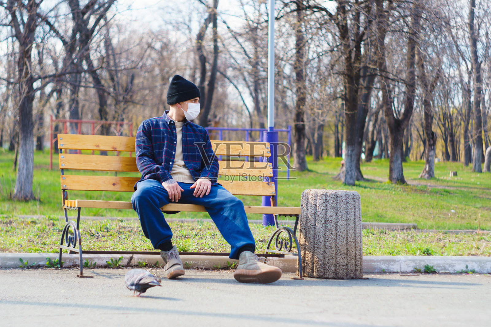 防护冠状病毒的医用口罩。一个人坐在长凳上照片摄影图片