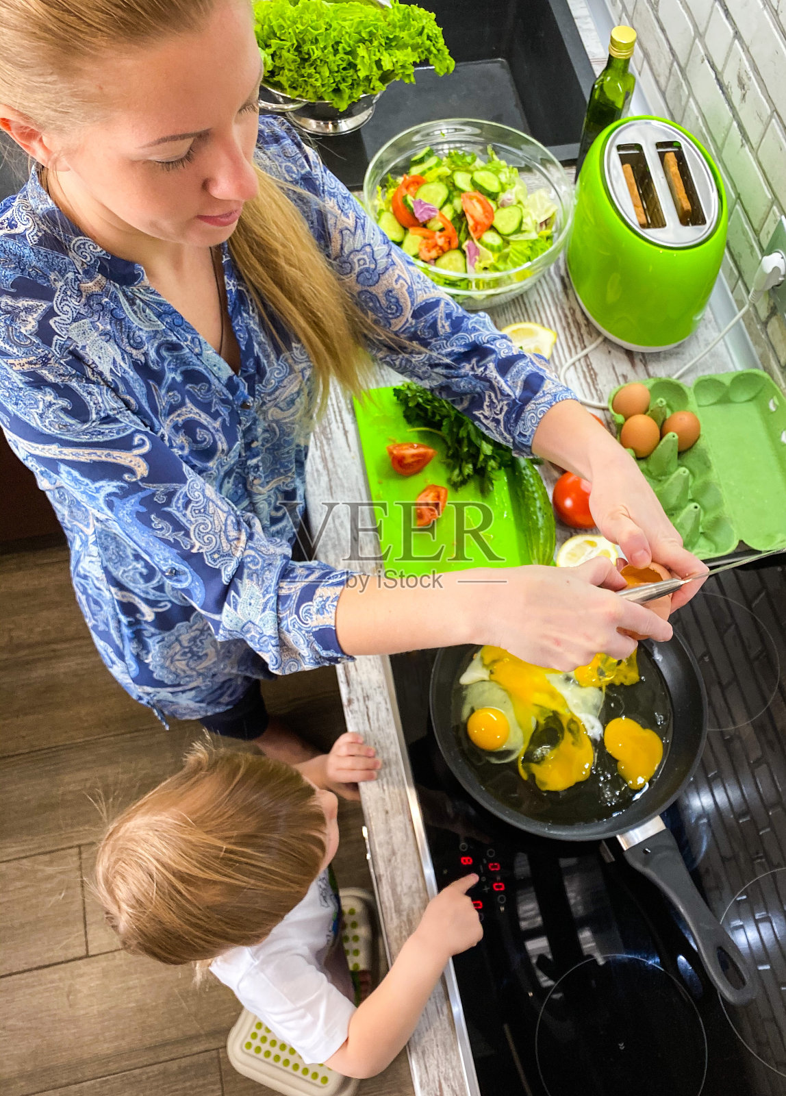 皮肤白皙的妈妈和儿子在家里的厨房里准备食物/早餐。照片摄影图片
