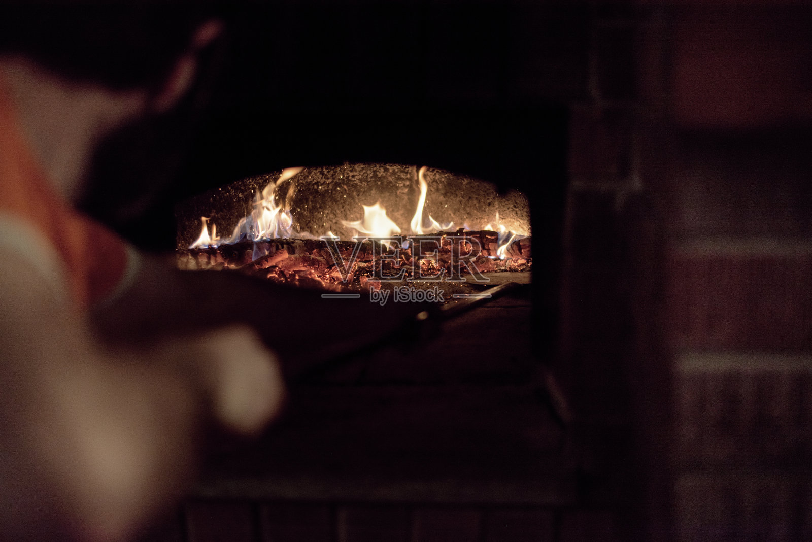 烤箱中的木头燃烧:一个人在烘烤烤箱托盘之前移动余烬照片摄影图片