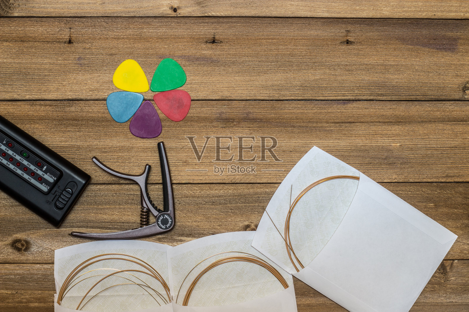 木背景上的木吉他配件，弦，拨片和调音器照片摄影图片