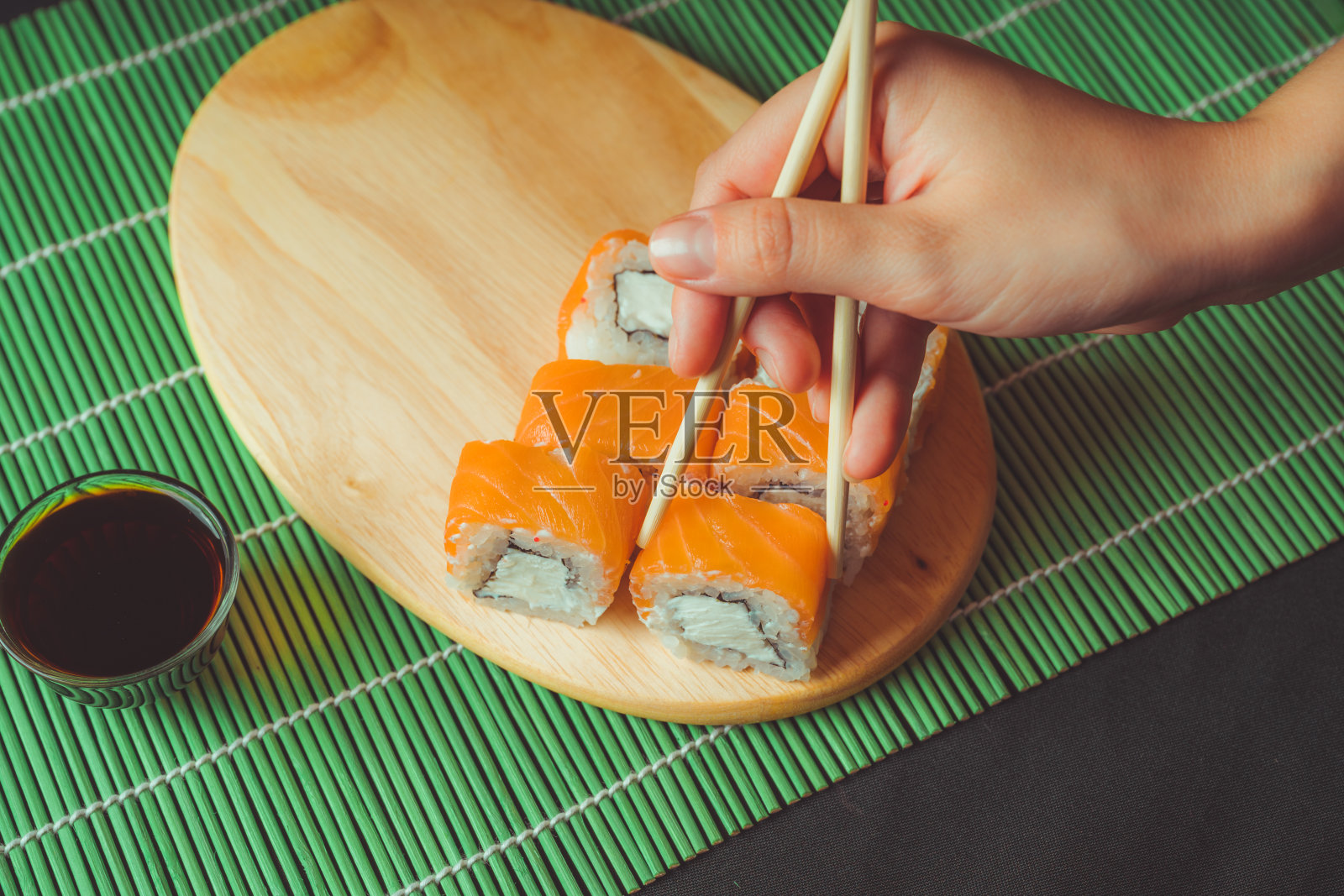 用筷子吃寿司卷。餐厅里的日本料理。女人用筷子夹寿司。日本食品的概念照片摄影图片