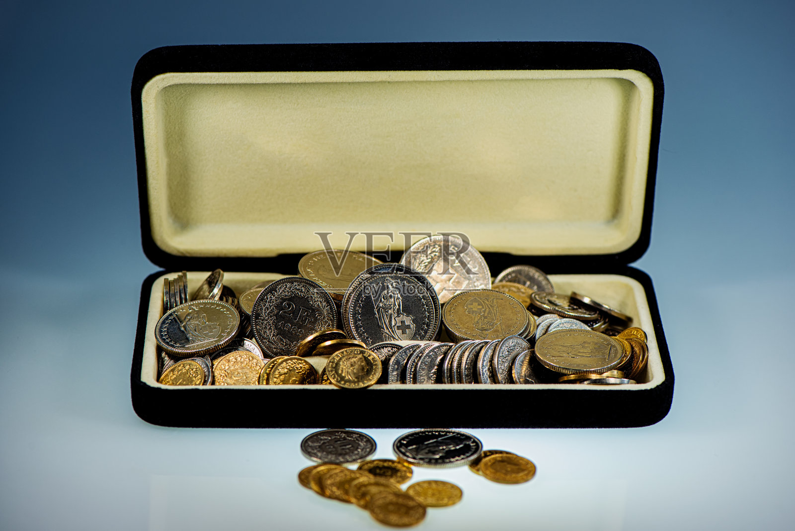 瑞士硬币和法郎放在一个以蓝色背景为背景的开着的盒子里照片摄影图片