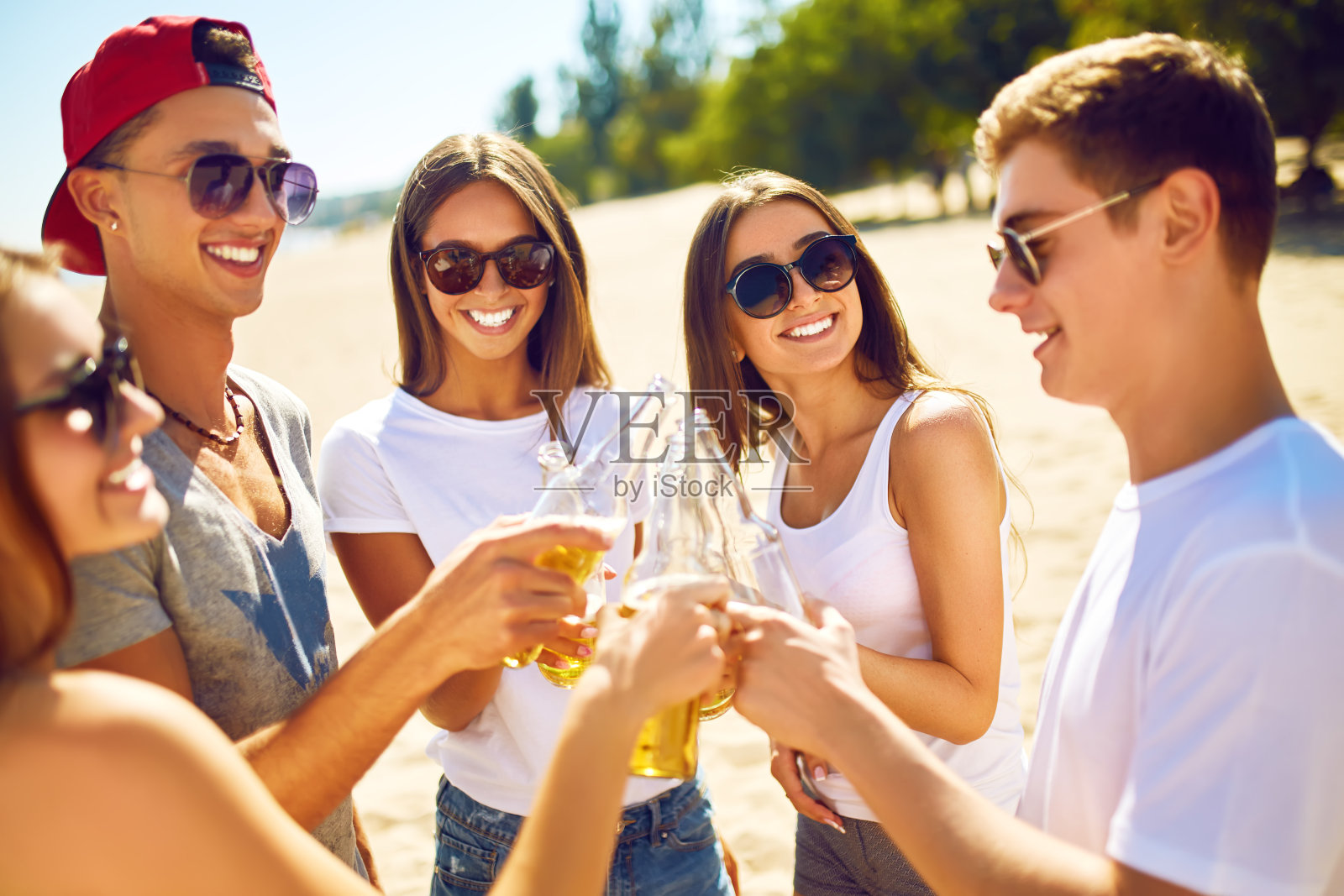 一群朋友在海滩上喝着啤酒玩乐。照片摄影图片