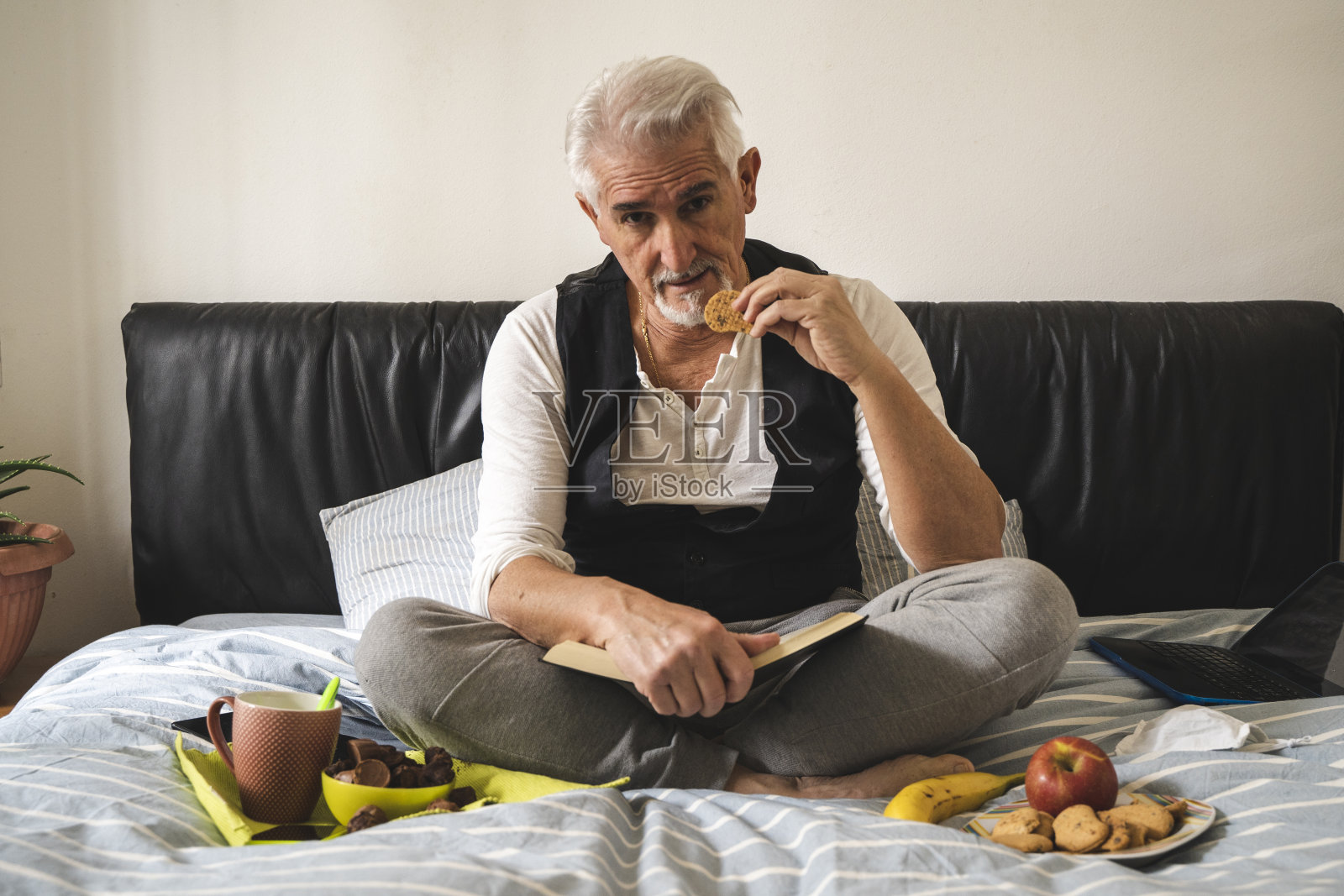 成熟的男人在床上吃早餐照片摄影图片